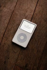 A classic white iPod with a circular touchpad placed on a wooden surface.