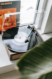 Stylish vintage vinyl record player in a cozy apartment setting with visible album cover.