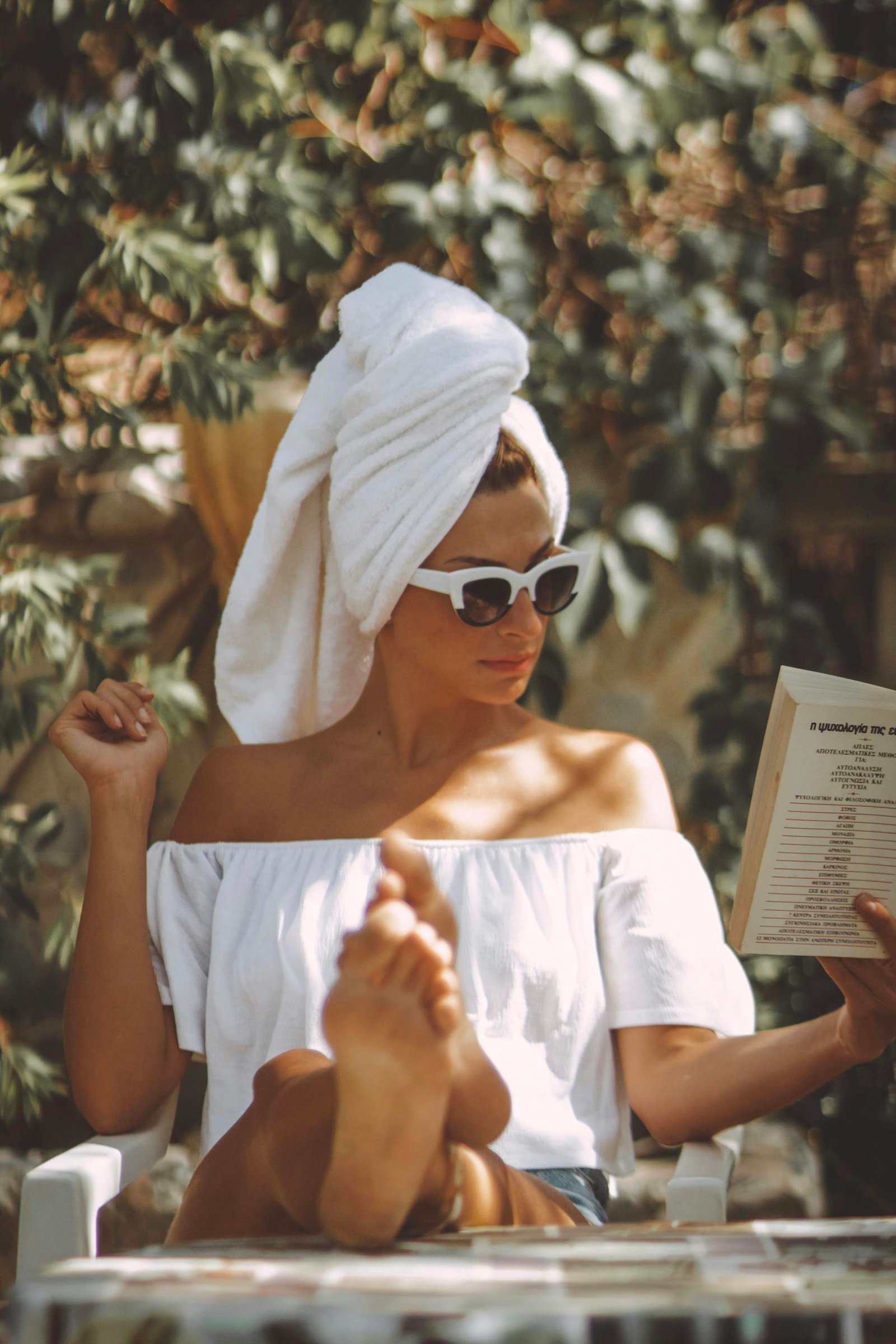 A stylish woman reads outdoors in summer, exuding elegance and leisure during her morning routine for success.