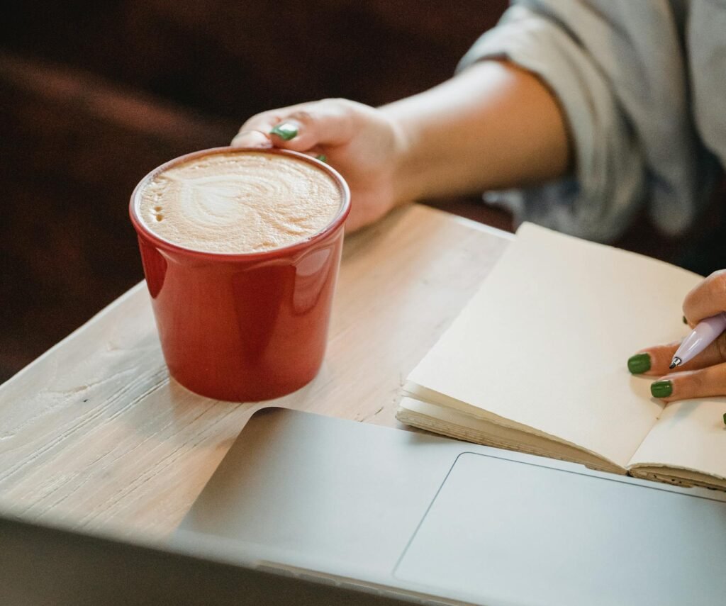 Person working with a laptop and coffee in a cozy café setting.