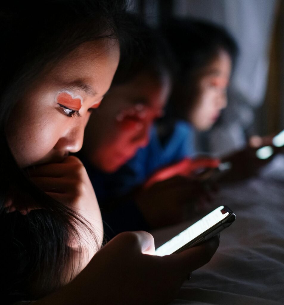 Three teenagers using smartphones in bed at night, highlighting modern digital habits, because they don't know how to stop scrolling addiction.
