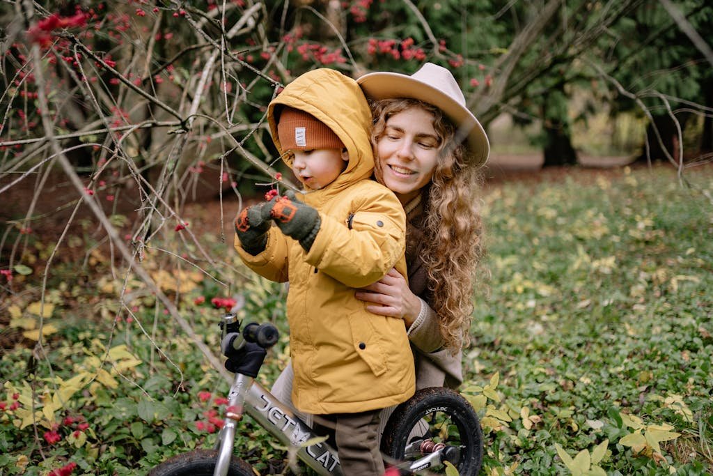 A joyful moment of a mother and child playing with a bicycle in an autumn park.