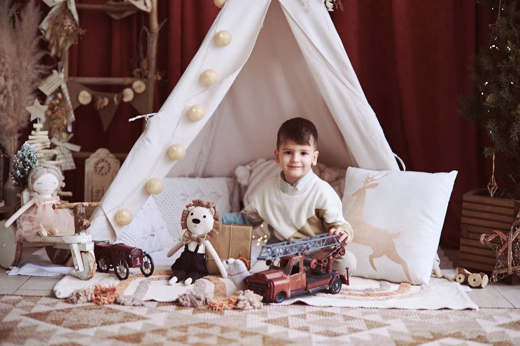 A young boy enjoys playing with toys in a cozy Christmas-themed tent setup.
