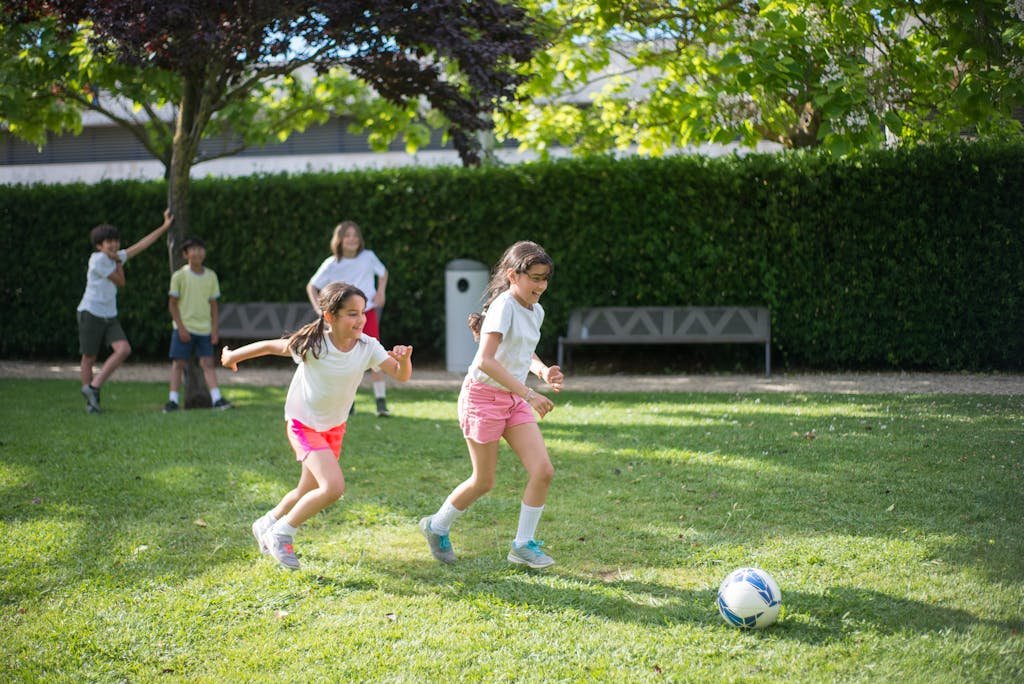 Children enjoy a game of soccer in a sunny park in Portugal, showcasing fun and leisure.