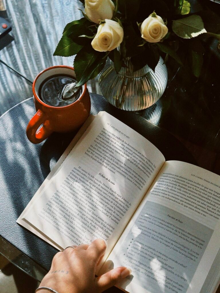Quiet morning reading ritual with an open book, black coffee, and fresh flowers in soft natural light.