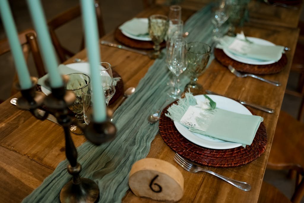 A beautifully arranged table setting with teal candles, plates, and decor for an elegant dinner.