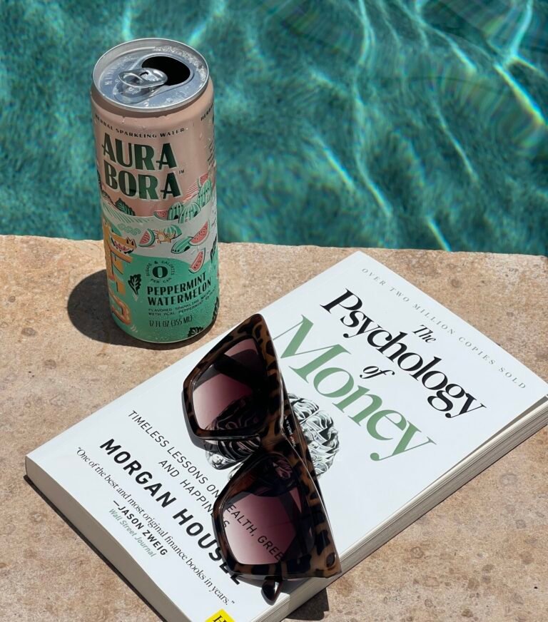 A can of soda, sunglasses and a book about financial goals