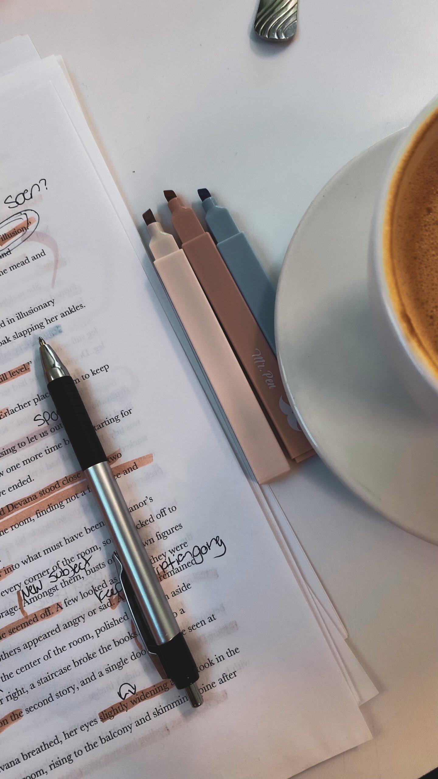 Annotated book pages with highlighters, pen, and coffee cup on a clean desk