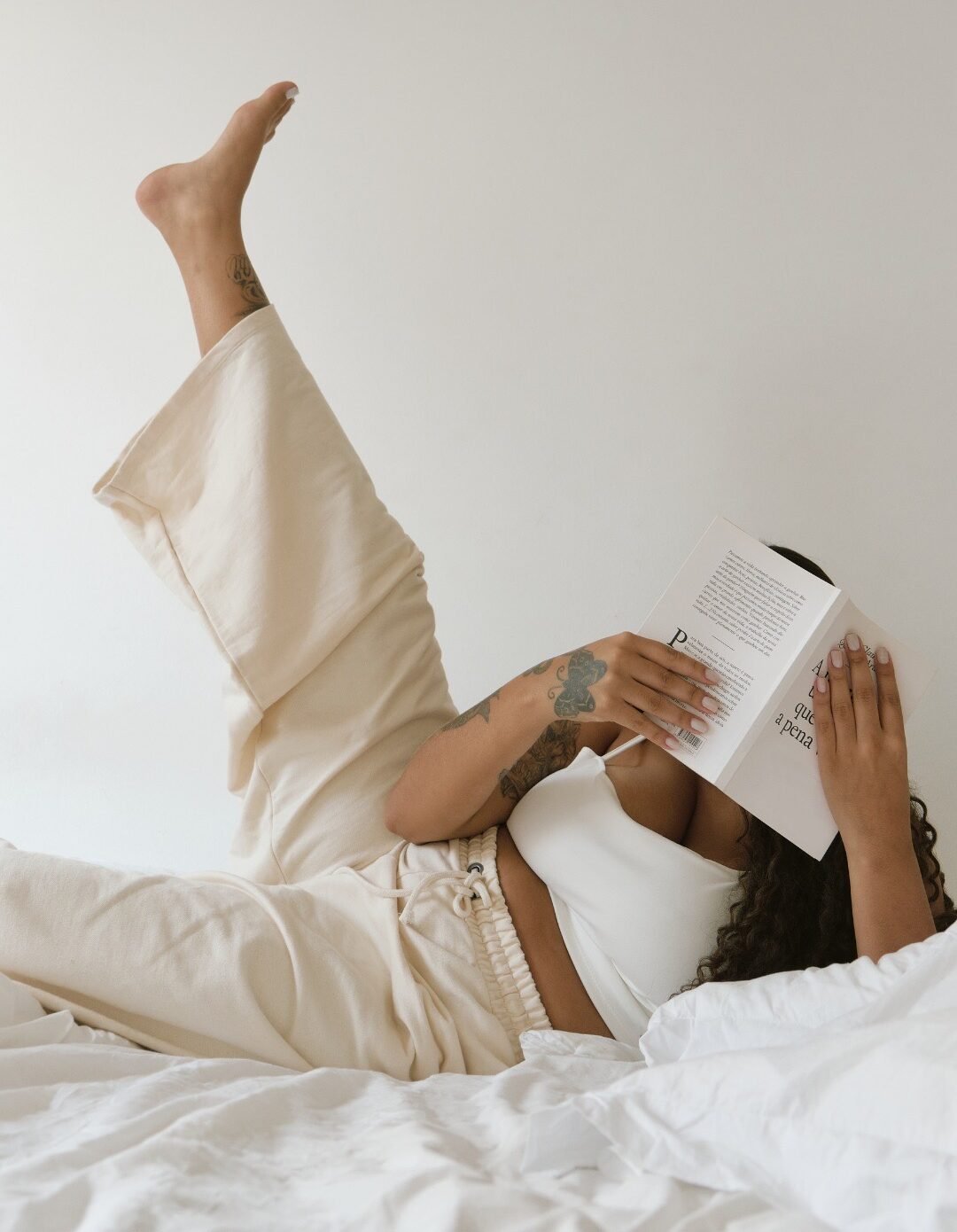 Procrastination scene with woman reading in bed instead of focusing on work