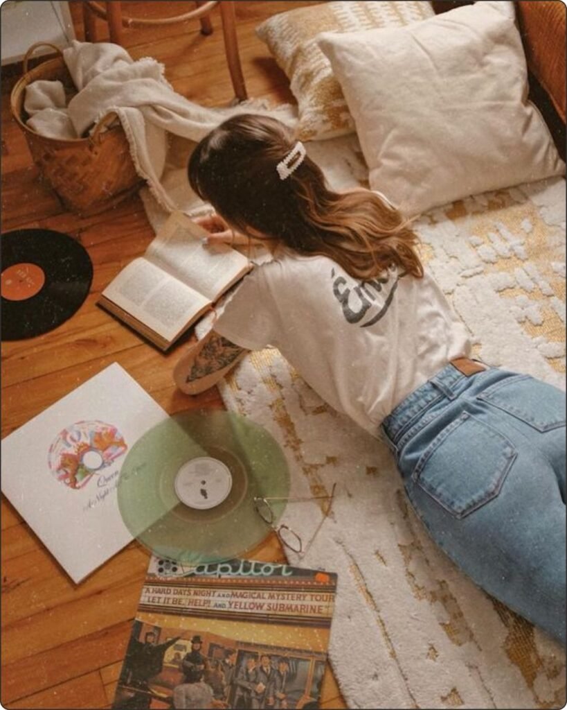 Woman laying on the flor next to a vinyl and reading a book, enjoying her analog hour