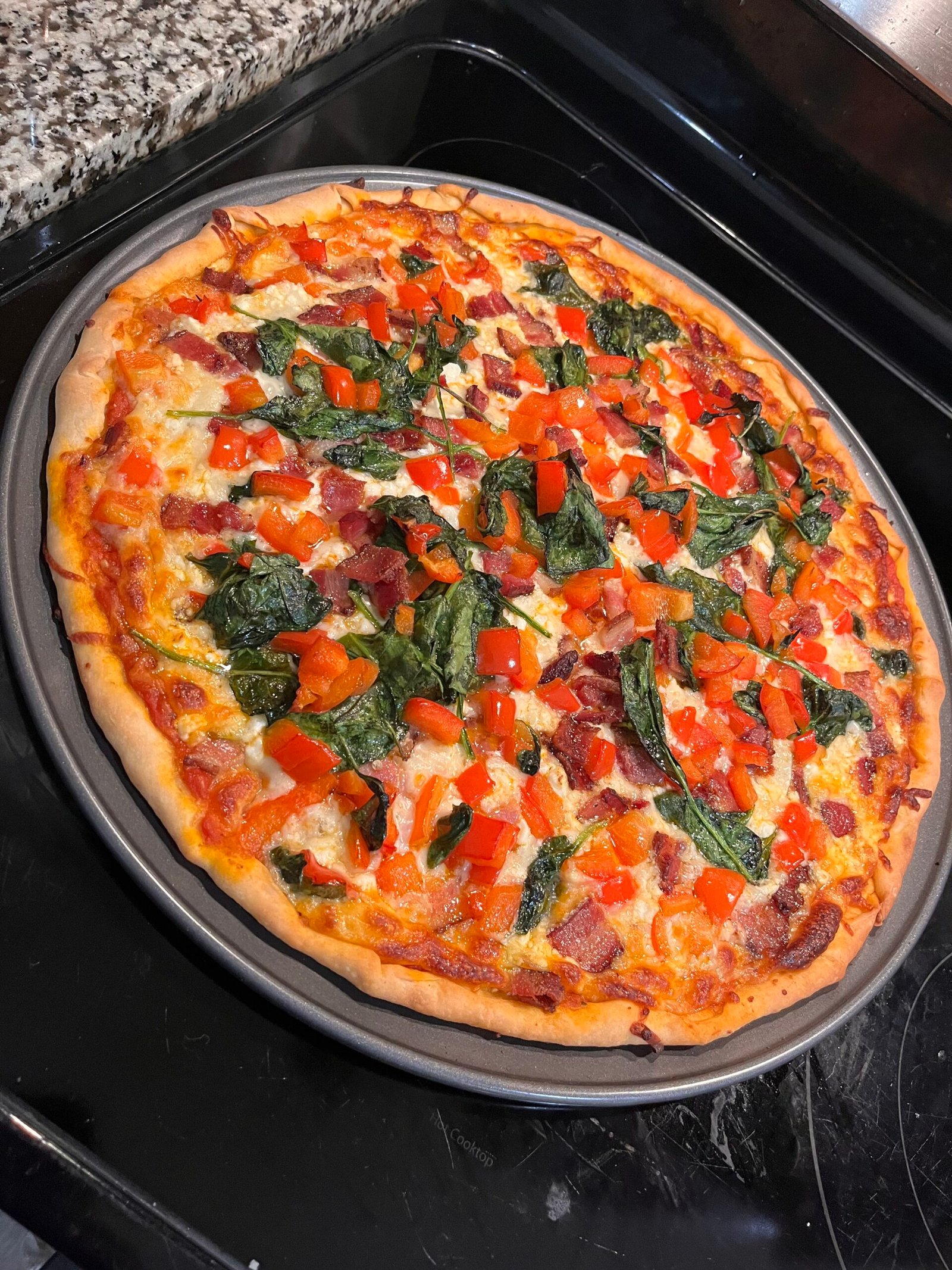 Homemade pizza with spinach, feta, peppers and bacon